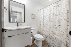 Bathroom with vanity, wood finished floors, visible vents, shower / tub combo, and toilet