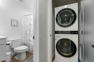 Washroom featuring visible vents, wood finished floors, laundry area, and stacked washer and dryer