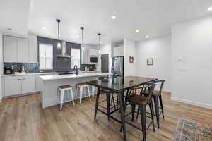 Interior space with decorative backsplash, white cabinets, appliances with stainless steel finishes, and wall chimney exhaust hood