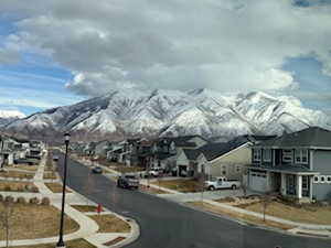 View of road with sidewalks, a mountain view, a residential view, and street lights