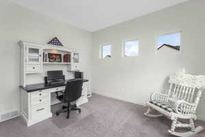 Office area with visible vents, baseboards, and light colored carpet