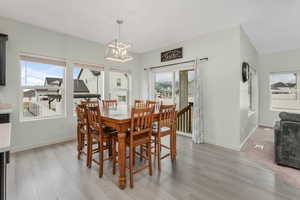 Dining space featuring a wealth of natural light, baseboards, light wood-style floors, and an inviting chandelier