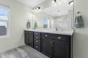 Bathroom featuring visible vents, a shower stall, baseboards, double vanity, and a sink