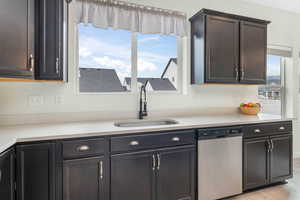 Kitchen with a sink, light wood finished floors, dishwasher, and light countertops