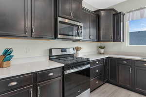 Kitchen with stainless steel appliances, light wood finished floors, and light countertops