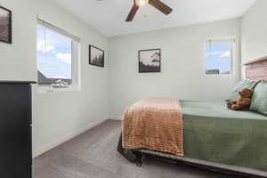 Carpeted bedroom with baseboards, multiple windows, and a ceiling fan