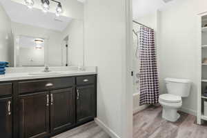 Full bath with visible vents, toilet, shower / tub combo, wood finished floors, and vanity