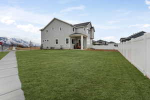 Back of house featuring a yard, a mountain view, stucco siding, and fence
