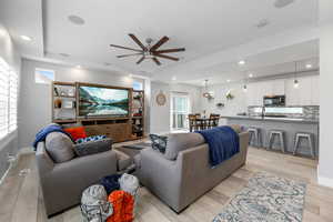 Premium living area with upgraded ceiling fan, visible vents, baseboards, light wood-style flooring, and recessed lighting