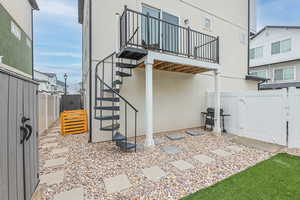 View of patio / terrace with spiral stairway, area for grilling, a vinyl fenced backyard, a gate, pavers with gravel and pavers