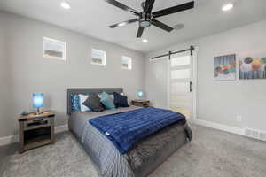 Bedroom featuring carpet flooring, visible vents, baseboards, and a barn door