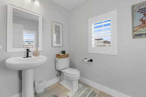 Half bath with natural light, large plantation shutters, water efficient toilet, large baseboards, podium sink with designed faucet