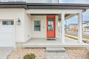 Entrance to property featuring covered porch, window, window door, stucco siding, steps, gravel, garage door with windows, street parking