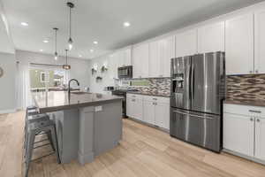 Kitchen featuring dark countertops, stainless steel appliances, tasteful backsplash, and a sink