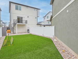 View of backyard, bbq area, deck, spiral staircase, vinyl fence, turf field, a gate, gravel and pavers