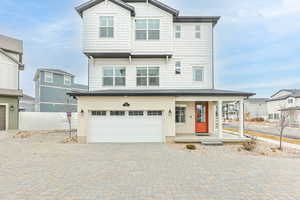 View of front facade featuring decorative driveway, a garage, a porch, and fence