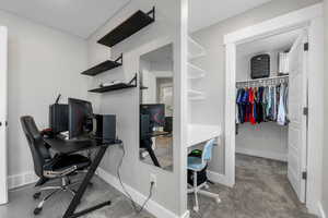 Room, with shelves, desk and walk-in closet with large baseboards, and carpet floors