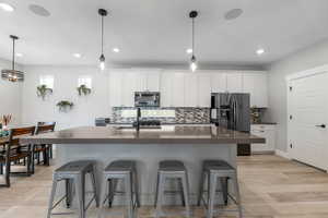 Kitchen featuring a kitchen breakfast bar, fridge with ice dispenser, dark countertops, and backsplash