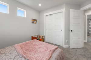 Carpeted bedroom with a closet, designed closet doors, recessed lighting, large baseboards, canister lights, windows