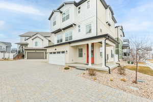 View of front of property featuring decorative driveway, a porch, and an attached garage