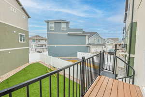 Balcony featuring a turf field and residential view, railing and spiral staircase, gravel, vinyle fence, pavers