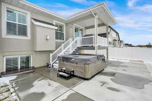 Exterior space with a patio area, stucco siding, a hot tub, and fence