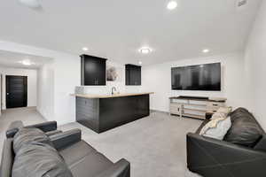 Living area with baseboards, visible vents, recessed lighting, indoor wet bar, and light carpet
