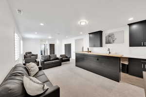 Living area featuring recessed lighting, indoor wet bar, light carpet, and visible vents