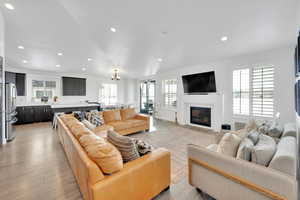Living room featuring a fireplace with flush hearth, recessed lighting, and light wood-type flooring