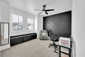 Office area with an accent wall, carpet flooring, baseboards, and ceiling fan