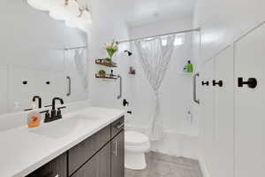 Bathroom featuring toilet, shower / bath combo, and vanity