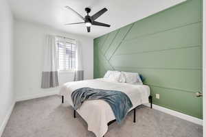 Carpeted bedroom featuring a ceiling fan and baseboards