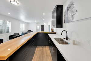 Kitchen with a sink, light wood-style flooring, a peninsula, and dark cabinets