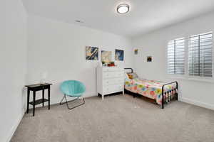 Carpeted bedroom with baseboards and visible vents