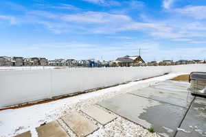 Snow covered patio with a residential view and a fenced backyard