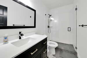 Bathroom with toilet, a stall shower, and vanity