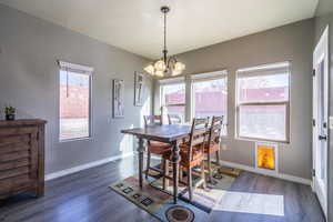 Dining space with baseboards, a textured ceiling, an inviting chandelier, and wood finished floors