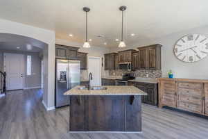 Kitchen featuring a sink, dark brown cabinetry, arched walkways, and stainless steel appliances
