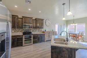 Kitchen featuring visible vents, a sink, backsplash, appliances with stainless steel finishes, and dark brown cabinets
