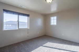 Spare room featuring carpet, visible vents, and baseboards