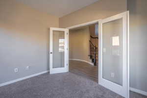 Unfurnished room with stairway, baseboards, carpet flooring, and french doors
