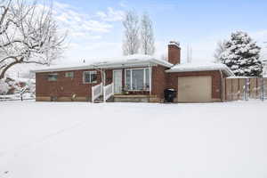 View of front of property with fence, brick siding, a garage, and a chimney