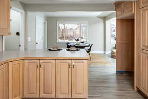 Kitchen featuring wood finished floors, light brown cabinets, baseboards, a peninsula, and light countertops