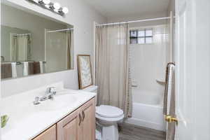 Full bathroom featuring shower / bath combination with curtain, toilet, vanity, and wood finished floors