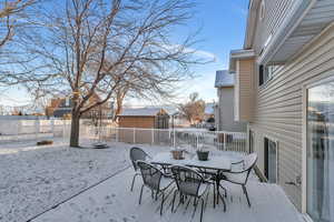 View of patio with outdoor dining space, a fenced backyard, an outdoor structure, a storage shed, and a residential view