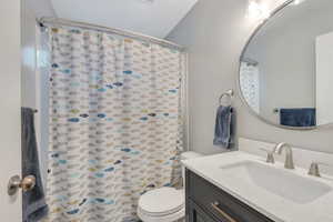 Bathroom with toilet, vanity, and a shower with curtain