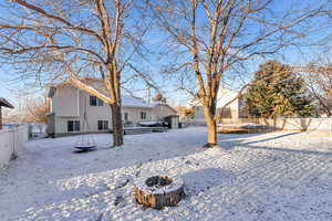 Yard layered in snow featuring a fire pit, a trampoline, and a fenced backyard