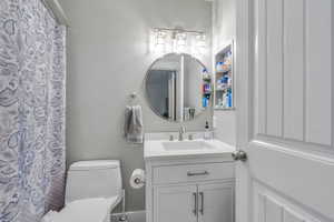 Bathroom with curtained shower, toilet, and vanity