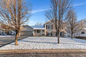 Split level home with a garage, brick siding, stucco siding, and aphalt driveway