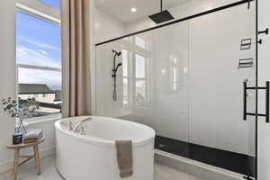 Bathroom featuring tile patterned flooring, baseboards, a stall shower, and a freestanding bath